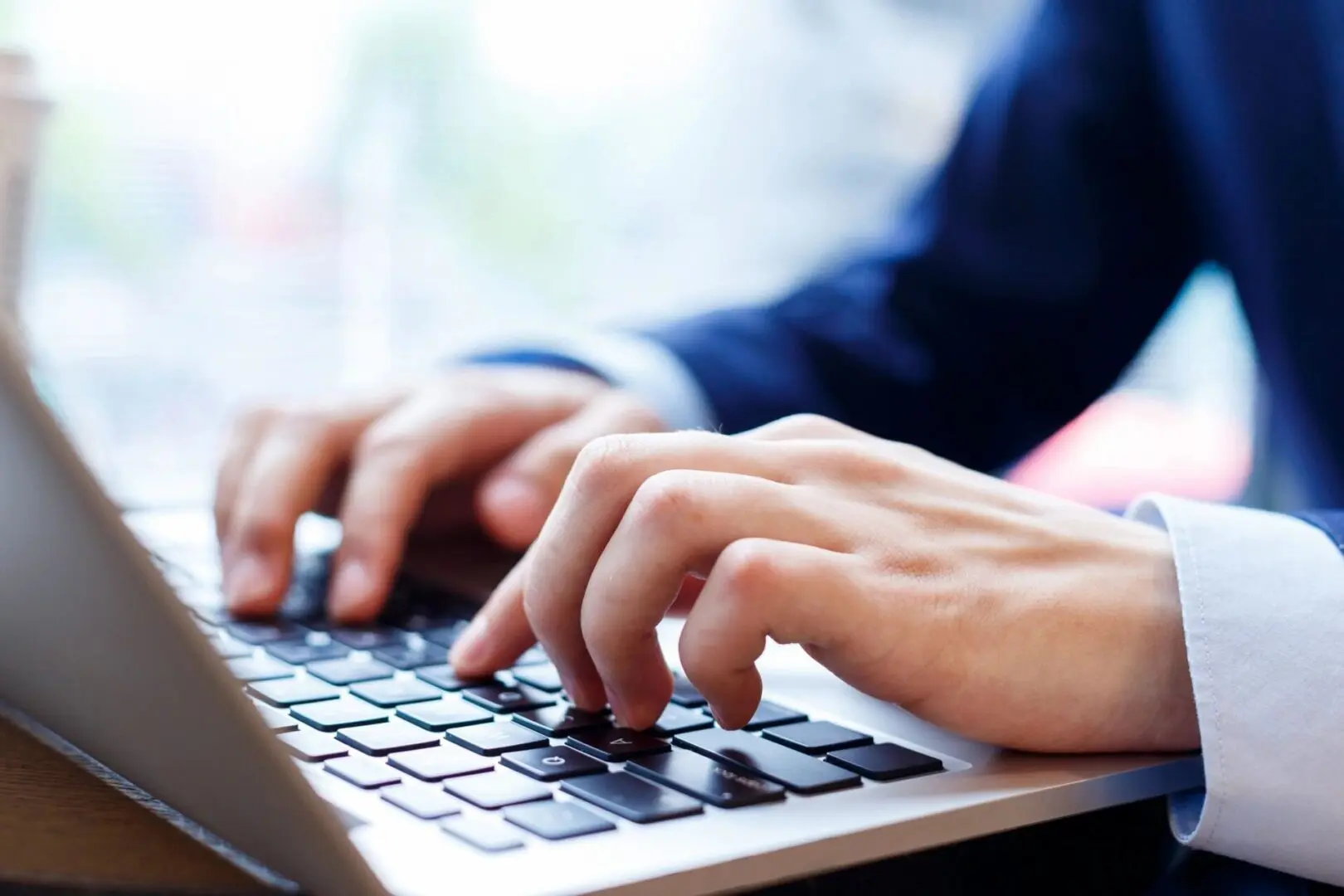 A person typing on a laptop keyboard.